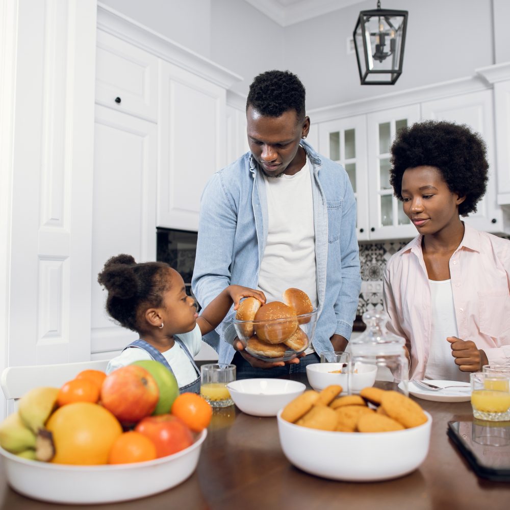 African parents with daughter enjoying breakfast at home