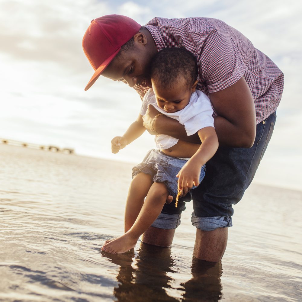 Father holding daughter (2-3) in sea